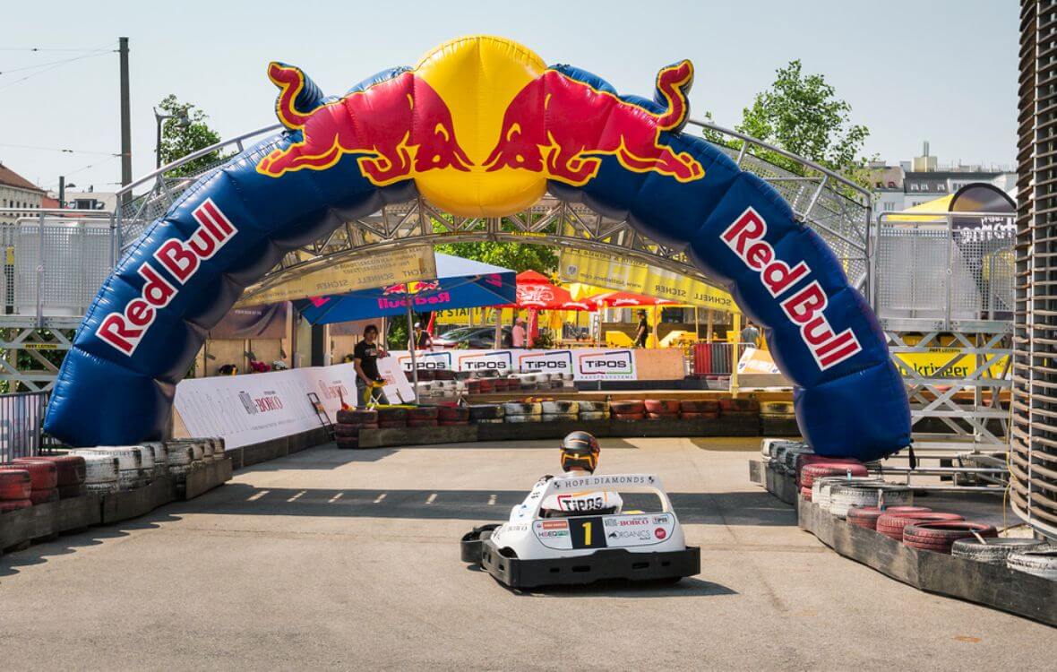 Bild eines Artofcart Events in Wien Ottakringer Brauerei. Kart Fahrer fährt durch den RedBull Bogen