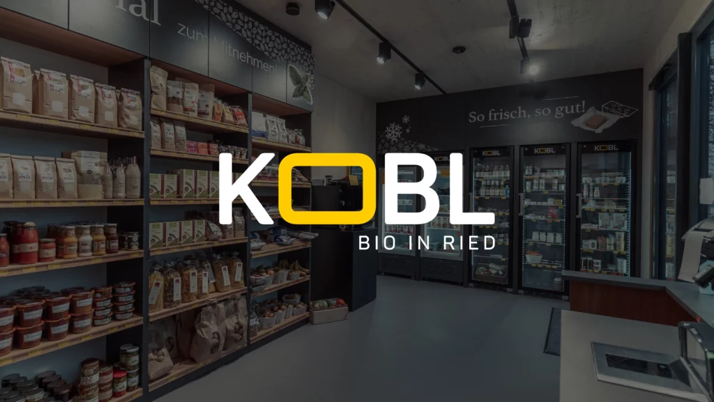 Kobl Logo in weiß vor dunklem Bild im Hintergrund welches den Innenraum eines Kobl Standortes zeigt.