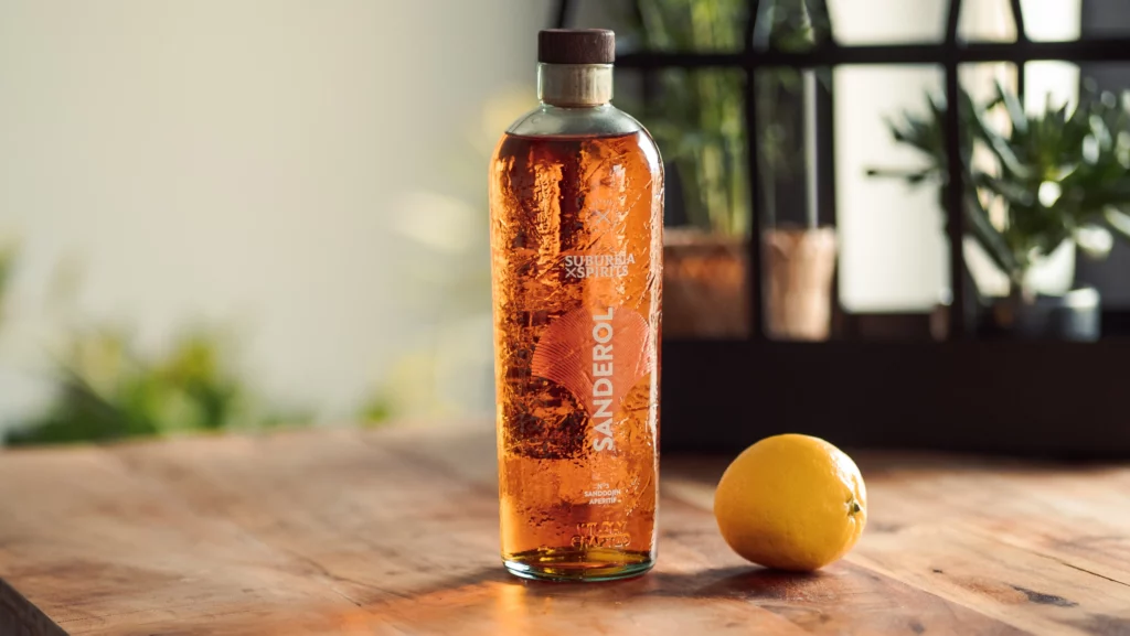 Imagefoto der Sanderol Flasche auf einem hölzernen Tisch daneben eine Zitrone