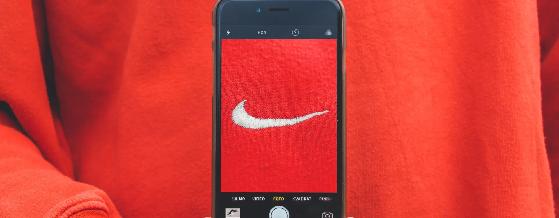 Eine Person macht ein Foto eines Nike Sweaters. Das Logo füllt dabei den gesamten Smartphone Screen