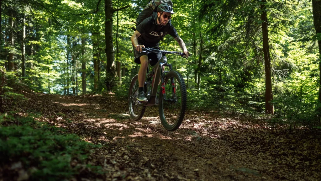 Mountainbiker im Sprung während dem Downhill fahren durch den Wald