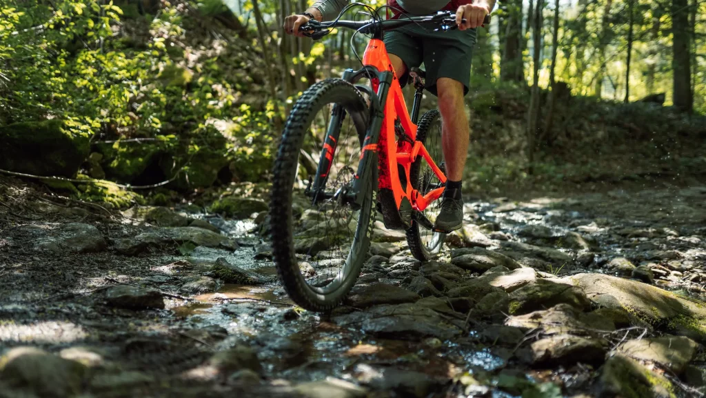 Mountainbiker fährt durch eine Wasserpfütze bei einer Walddurchfahrt