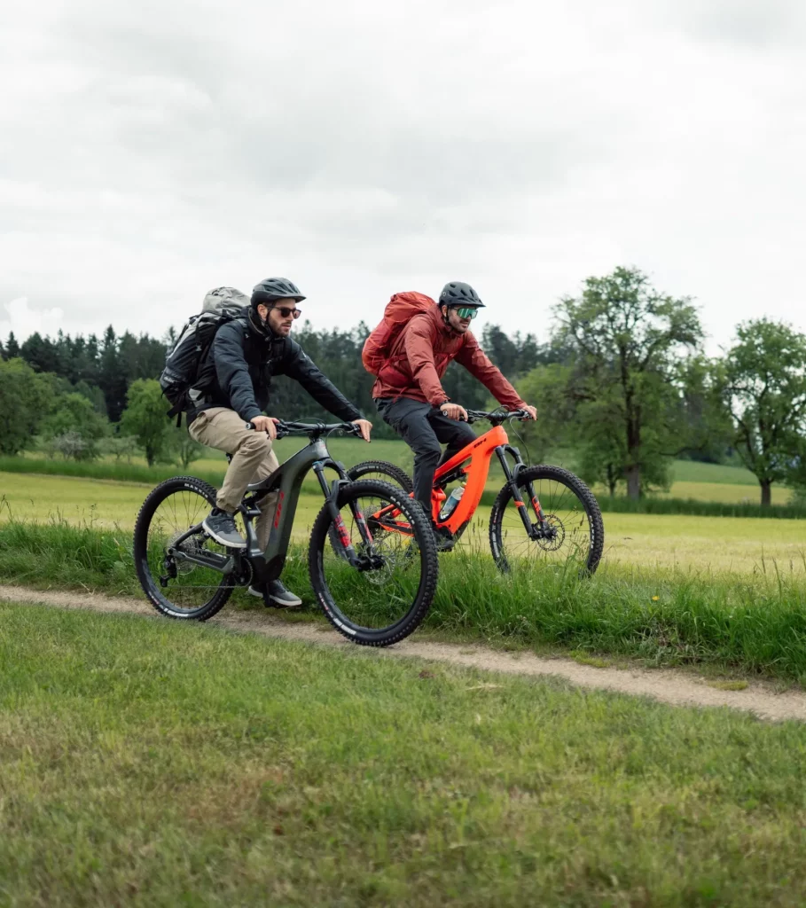 2 Mountainbiker fahren nebeneinander auf einem Feldweg.